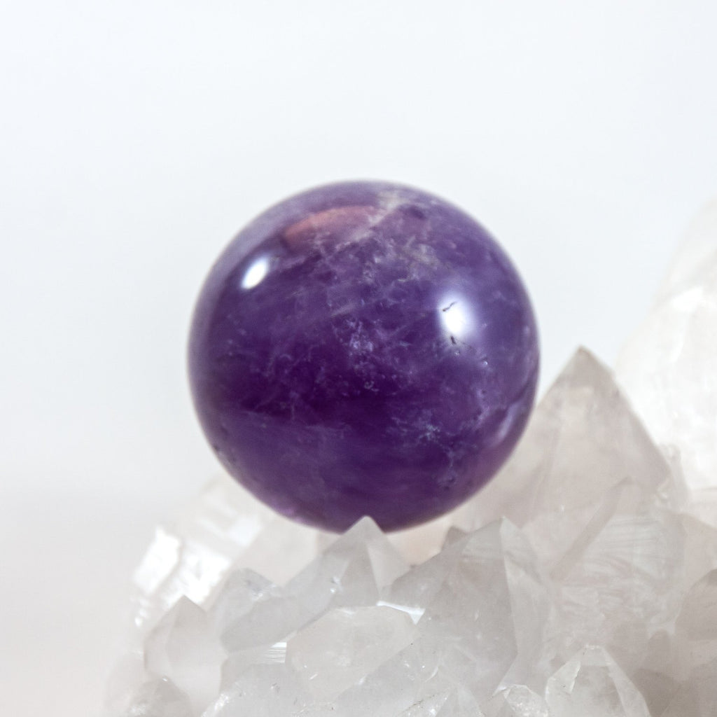 Amethyst equilibrium crystal sphere. Sitting on clear quartz crystal cluster.