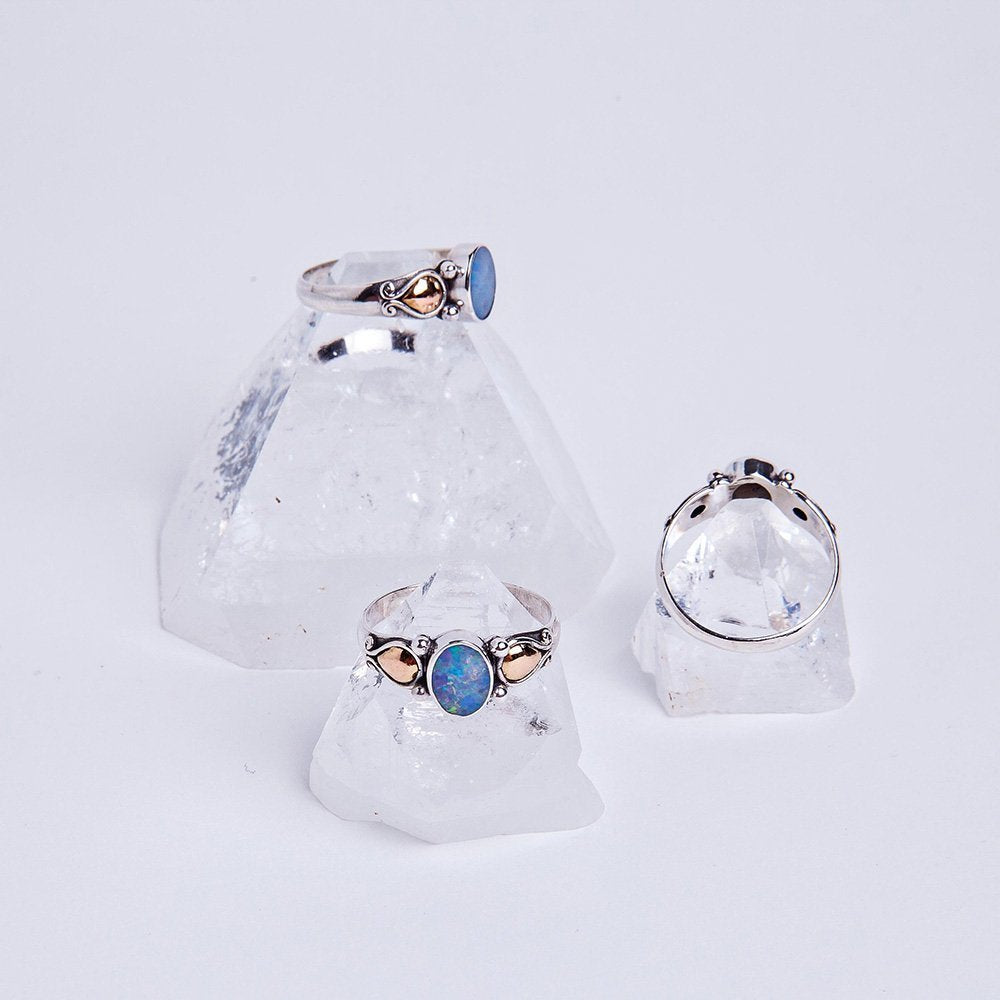 Three blue opal essence rings sitting atop apophyllite crystals.