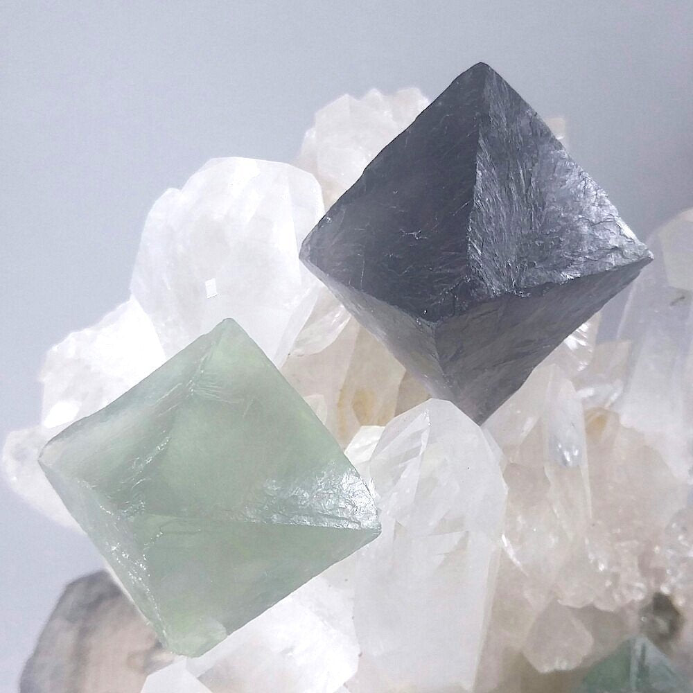 Two fluorite octahedron large crystals. Sitting on a quartz cluster.