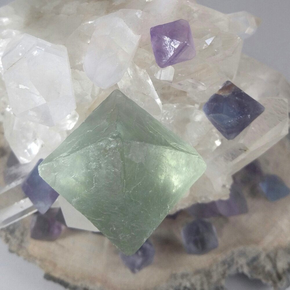 Fluorite octahedron large crystal with medium fluorite octahedron crystals. Sitting on a quartz cluster.