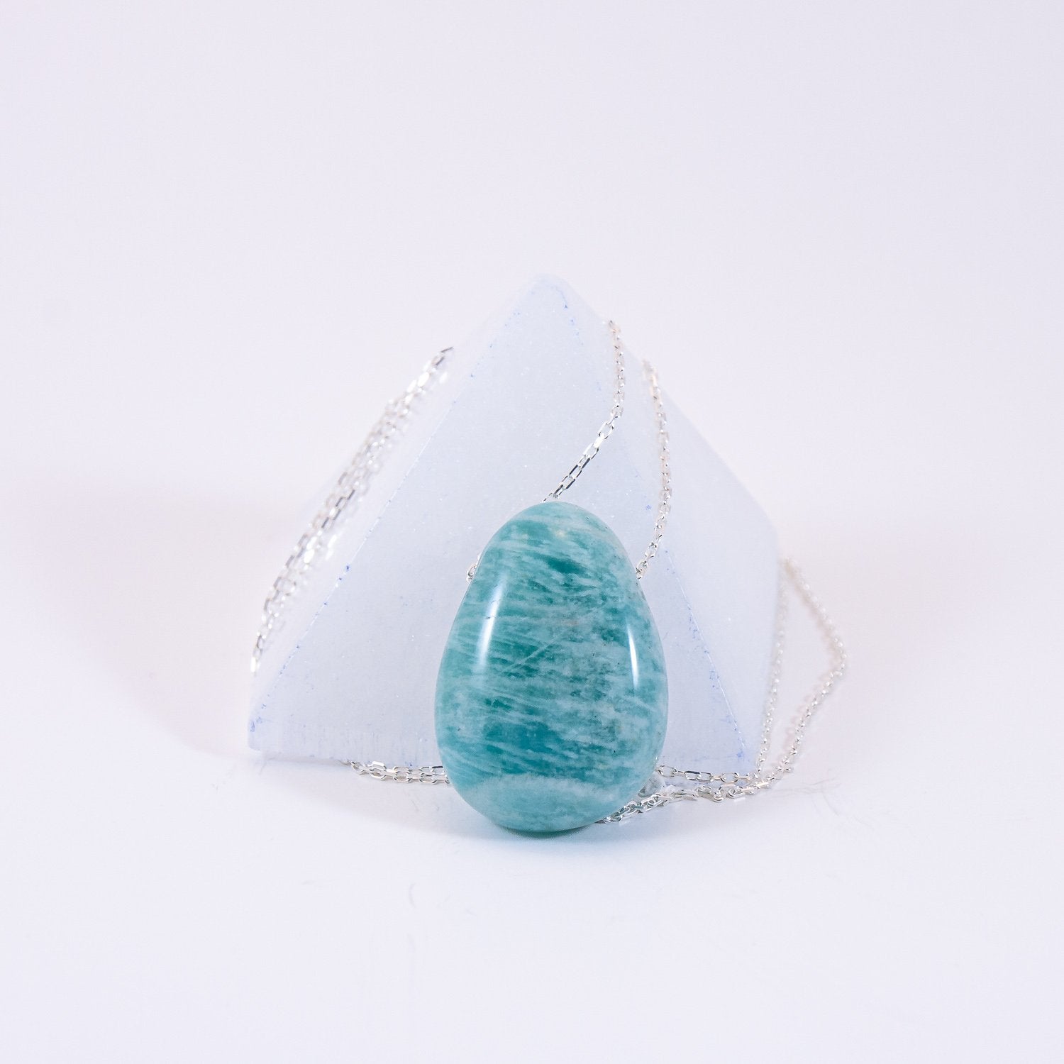 amazonite crystal drop pendant necklace on sterling silver chain. set in front of a selenite pyramid. 