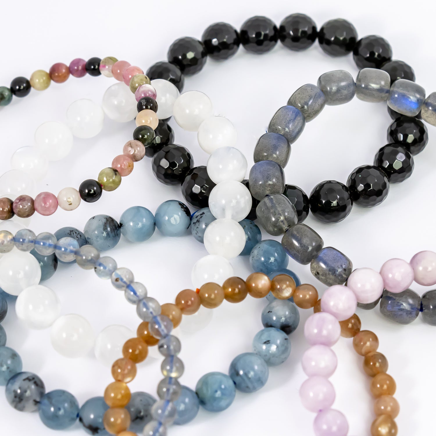 crystal bracelets (kunzite, labradorite large, labradorite small, peach moonstone, aquamarine, faceted black obsidian, moonstone, watermelon tourmaline) close-up.