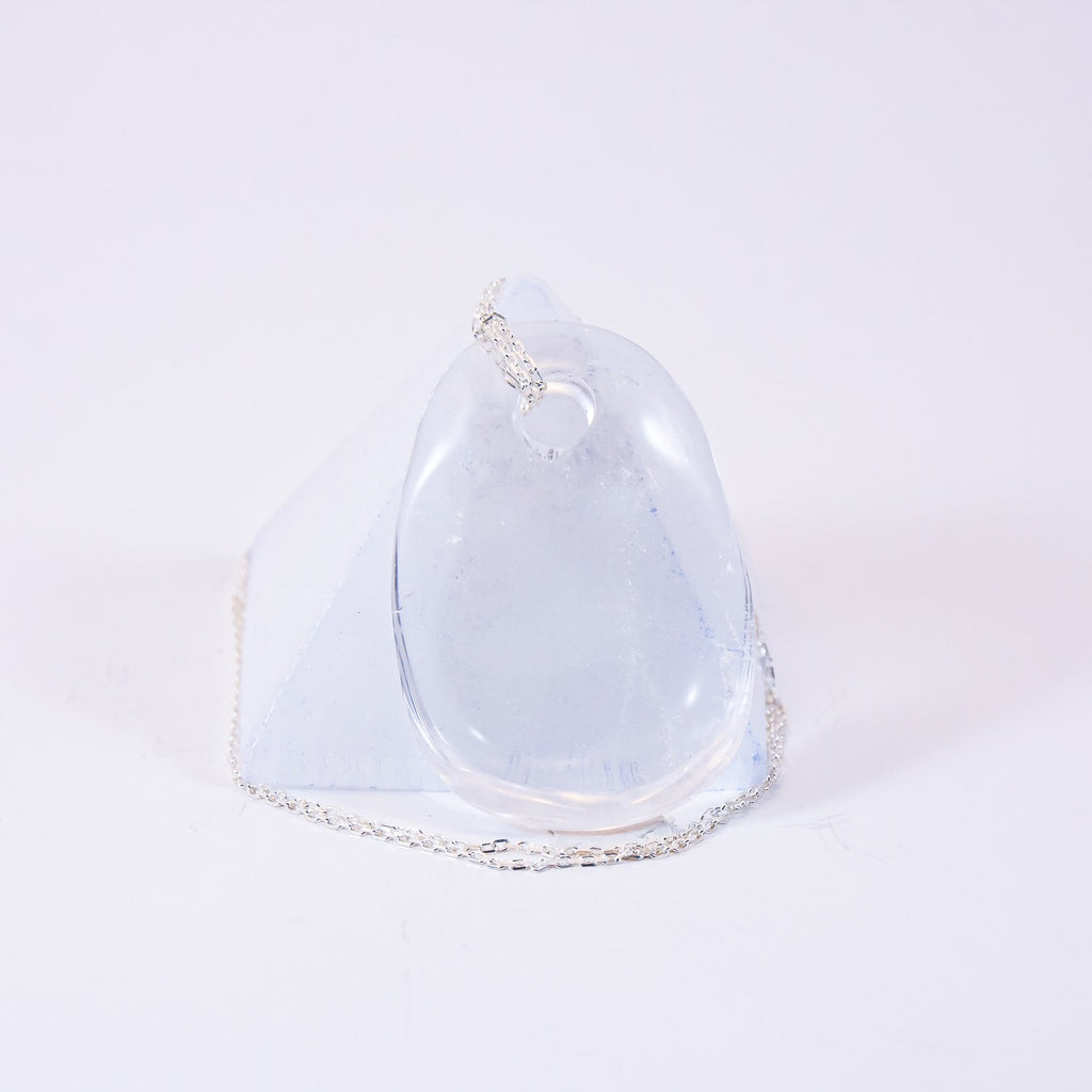 clear quartz crystal drop pendant necklace in front of selenite pyramid. sterling silver chain.