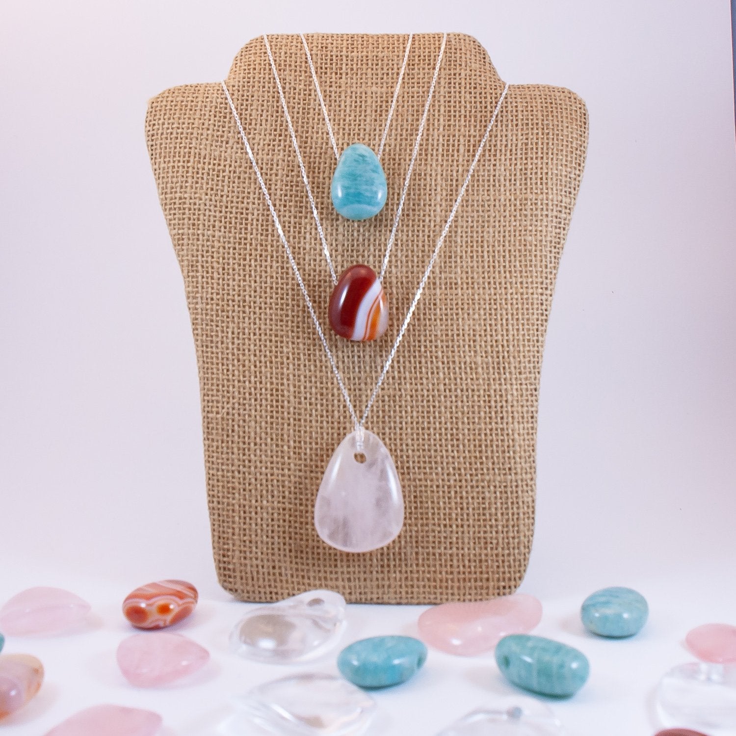 Crystal drop pendant necklaces on necklace display. Amazonite, carnelian, and clear quartz.