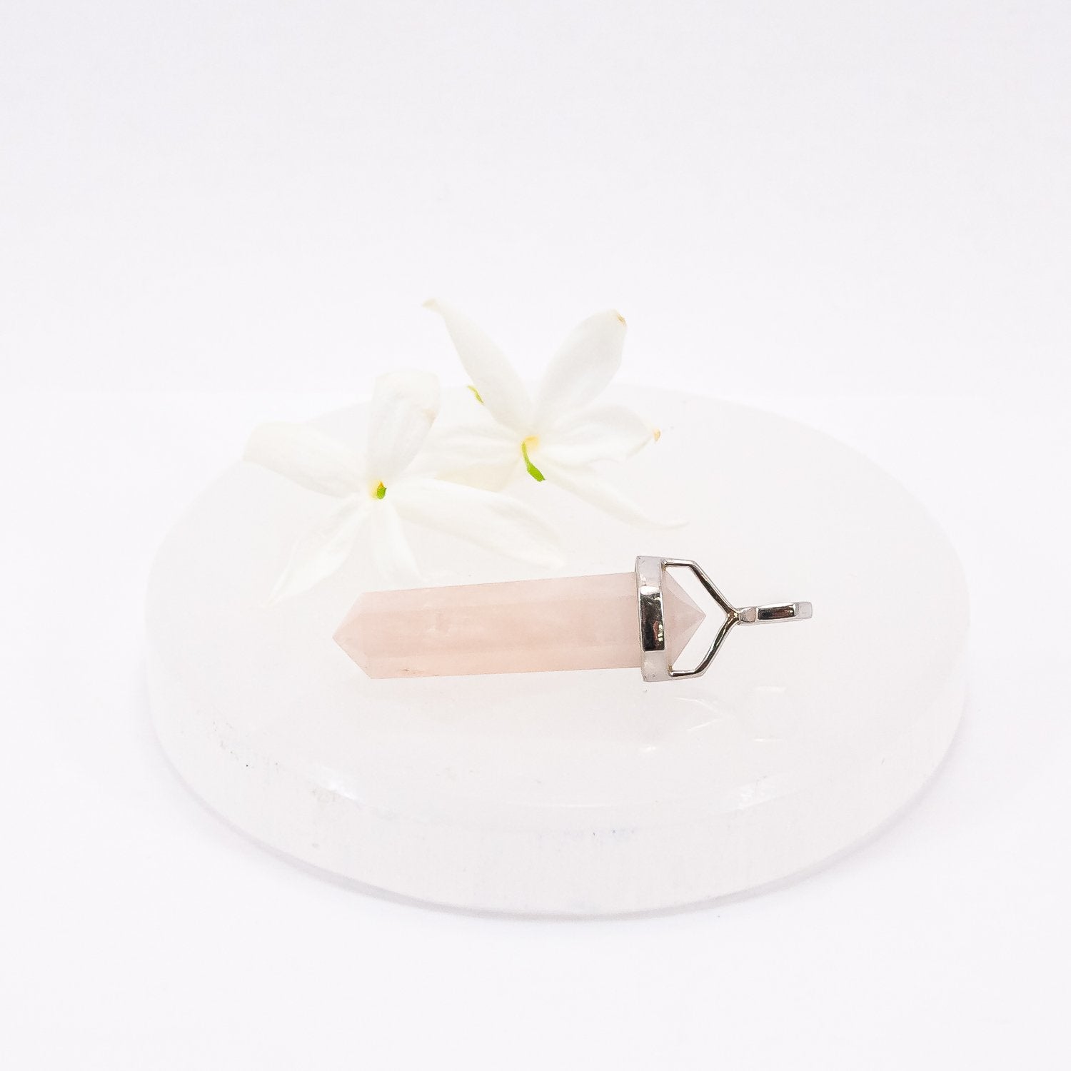 Morganite crystal pendant necklace on selenite plate with flowers.