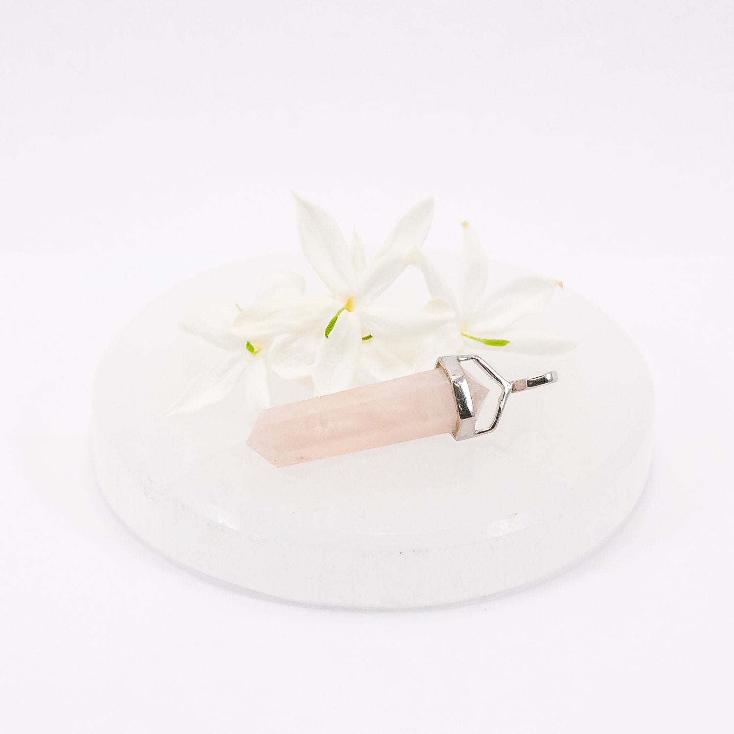 Morganite crystal pendant necklace on selenite plate with flowers.