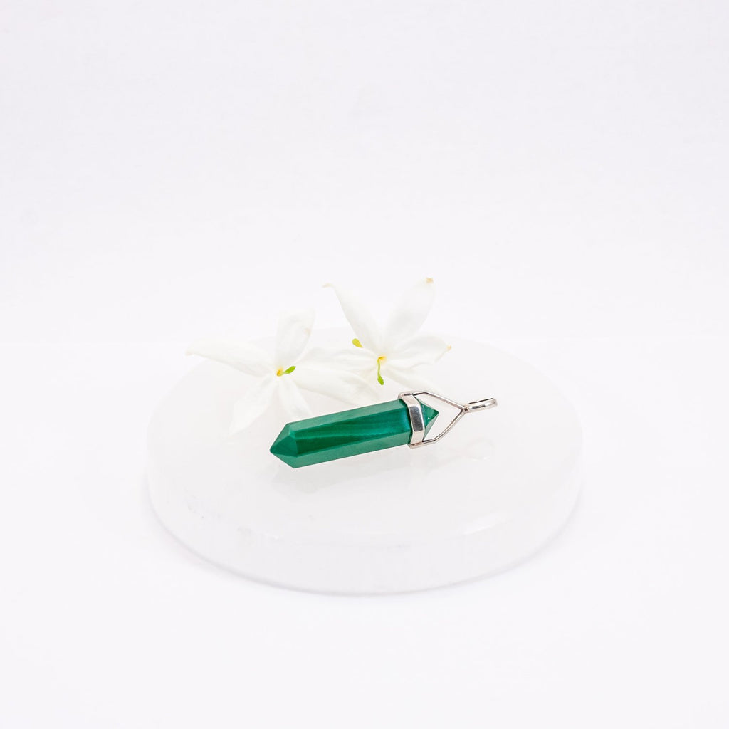 malachite crystal pendant. sitting with flowers on a selenite circle.