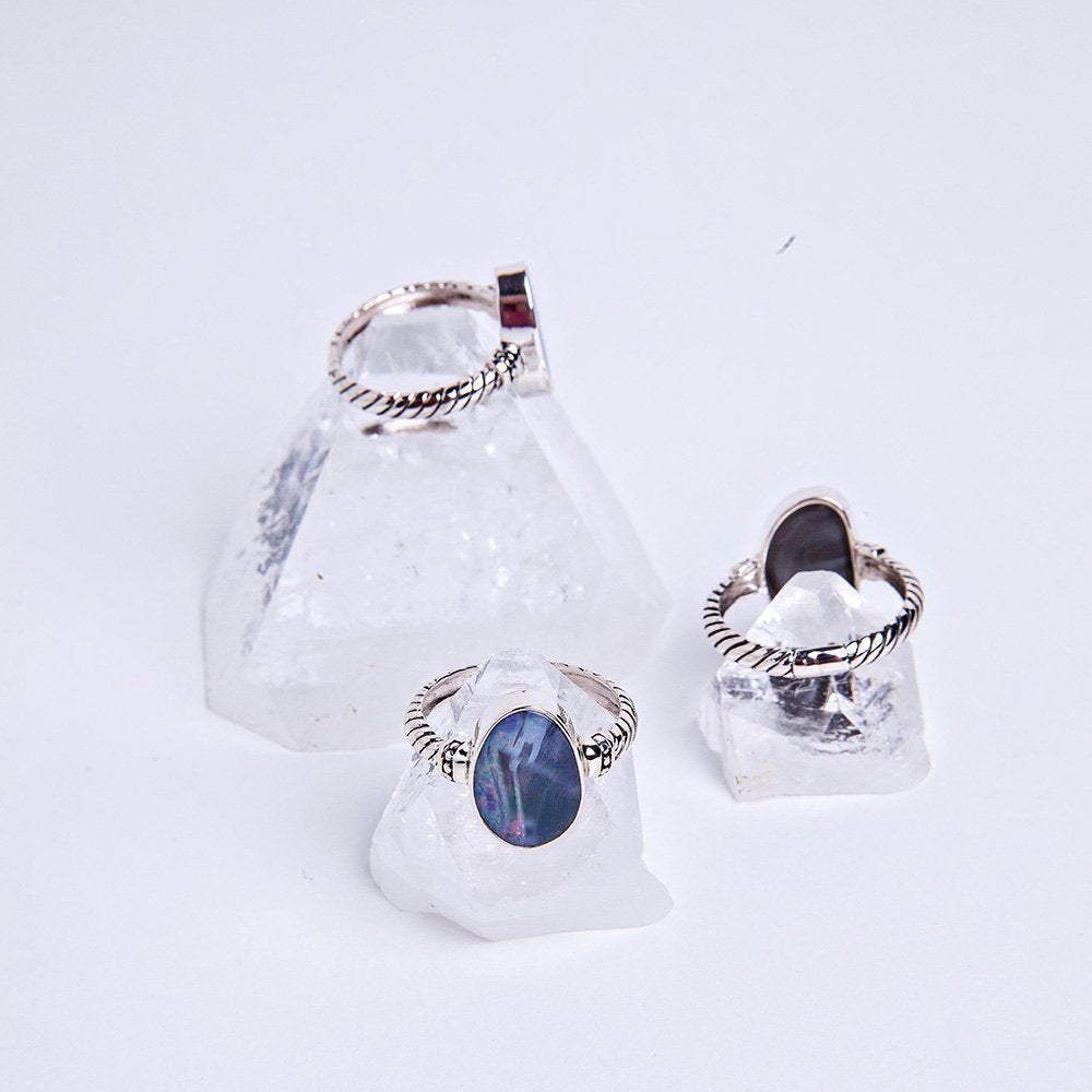 Three blue opal essence curve sitting atop apophyllite crystals.