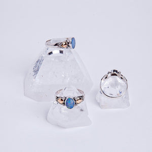 Three blue opal essence rings sitting atop apophyllite crystals.
