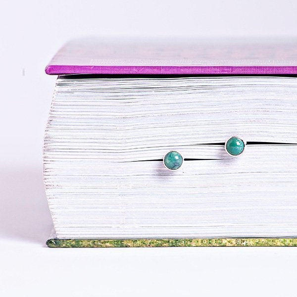 turquoise round cab earrings set in book pages for interesting aesthetics.